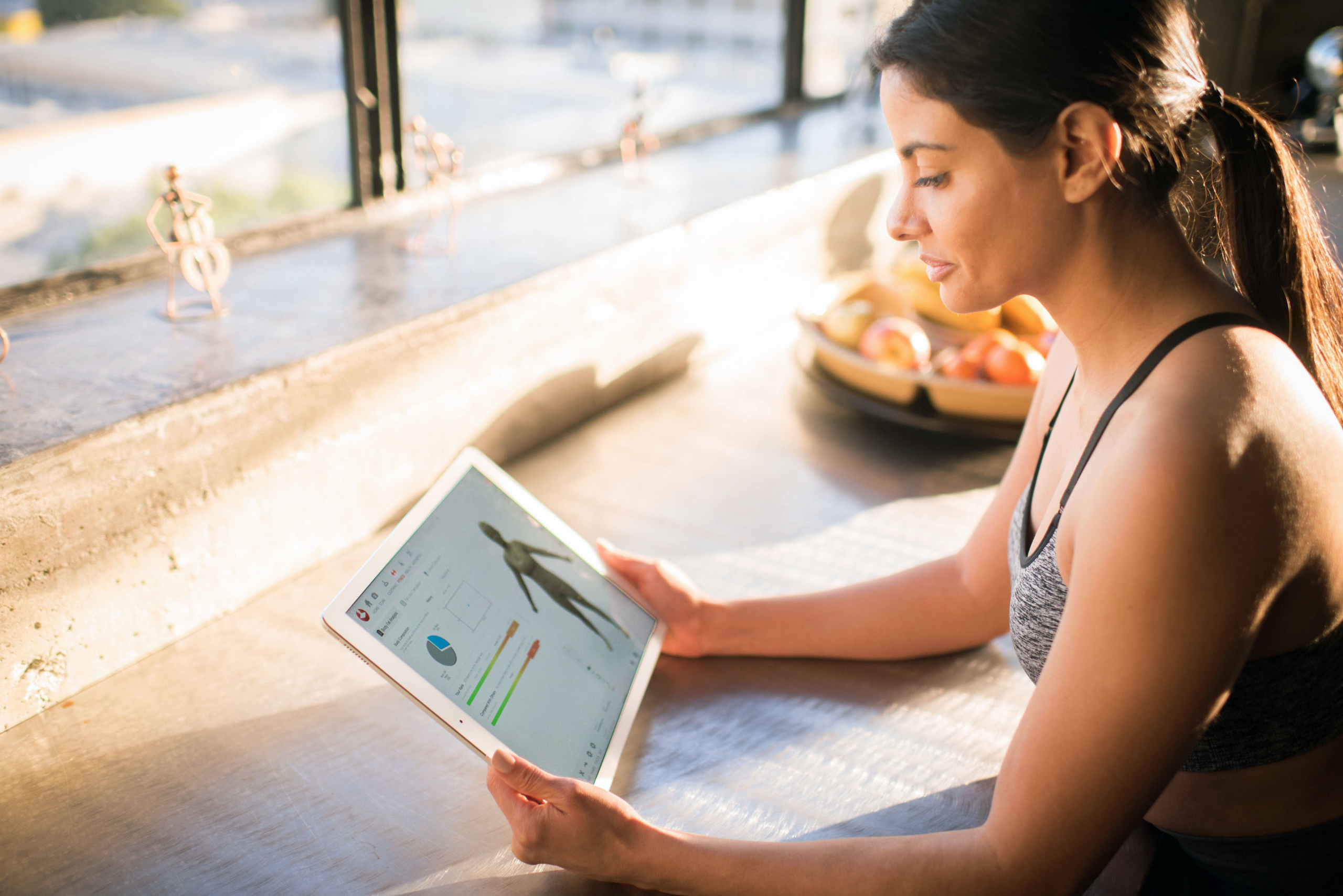 Woman reviewing her Styku 3D body scan results on a tablet at Sarani Wellness